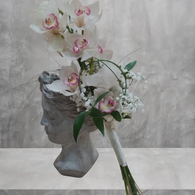 Composición de orquídeas rosadas sobre un busto de escayola