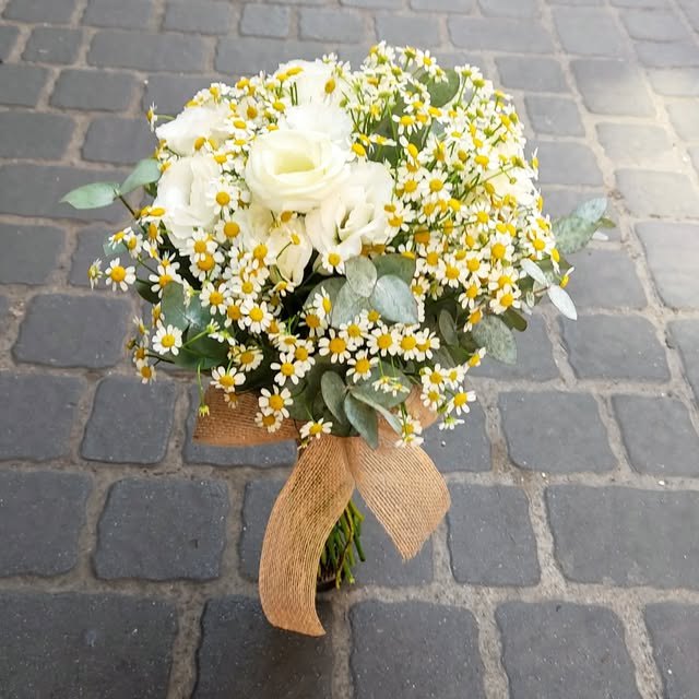 Ramo de rosas blancas y matricaria atado con lazo de rafia